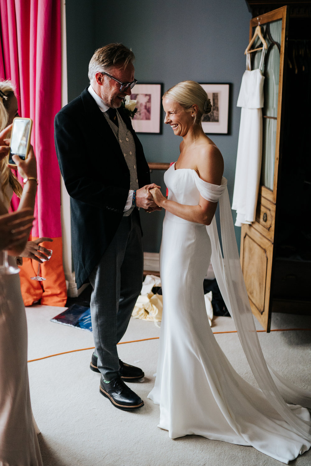  Father of the bride and bride hold hands as he sees her in her dress for the first time 