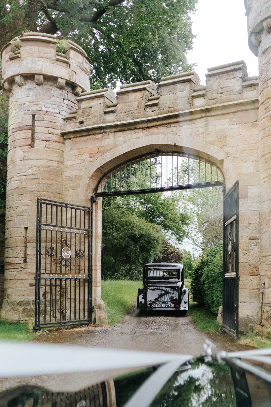Bride's car passes under fortified gates at Hawarden Castle in Wales, UK