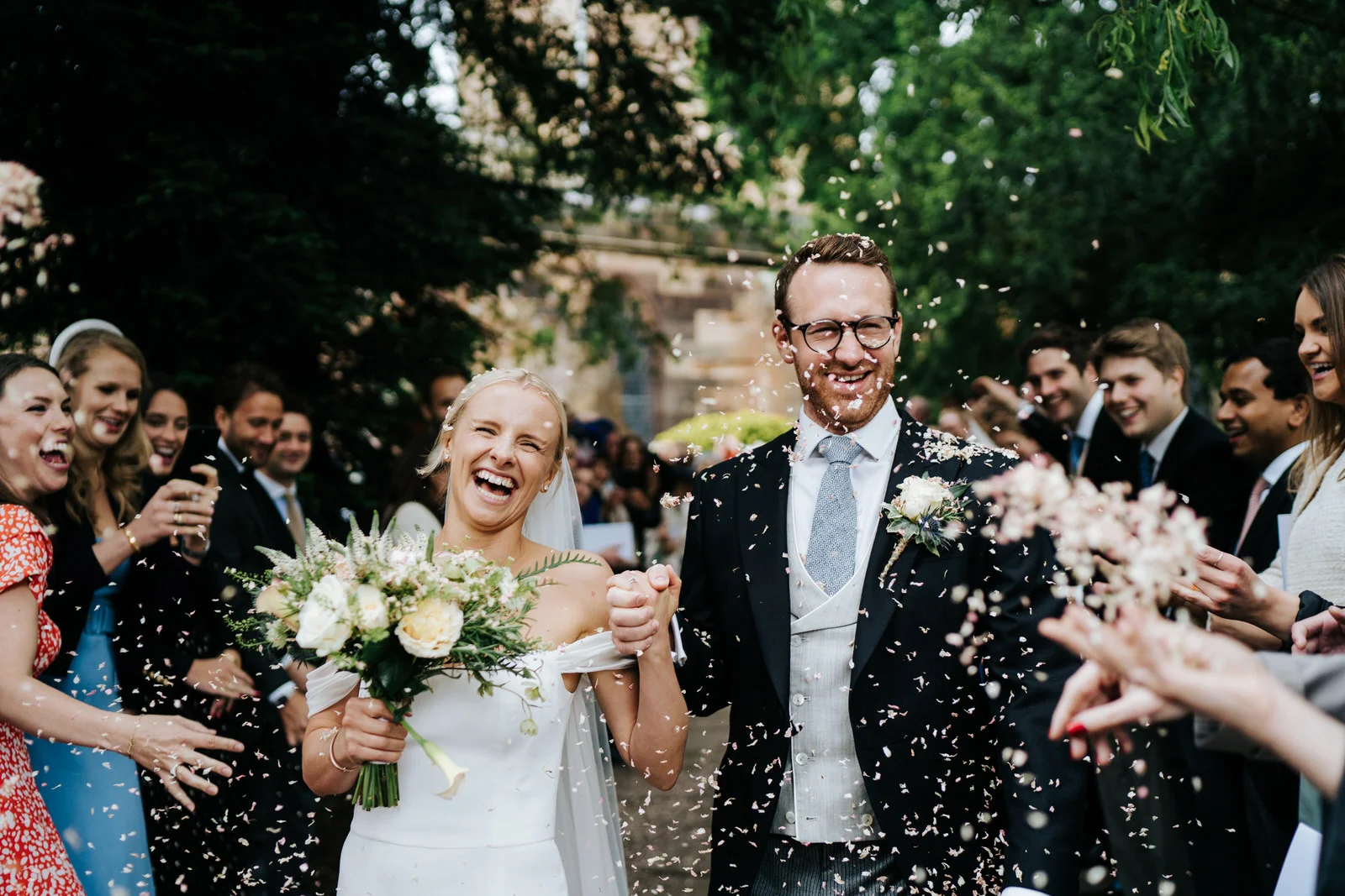 Bride and groom exit the church and walk down the pathway as guests throw confetti at them