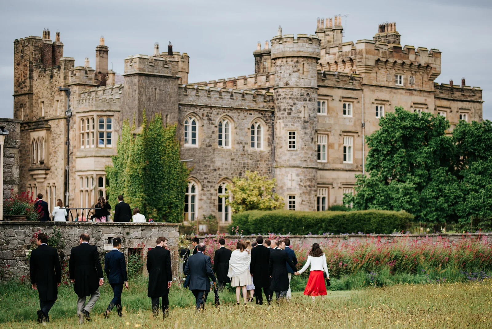 Guests and family walk across the lawn towards Hawarden Castle for the drinks reception