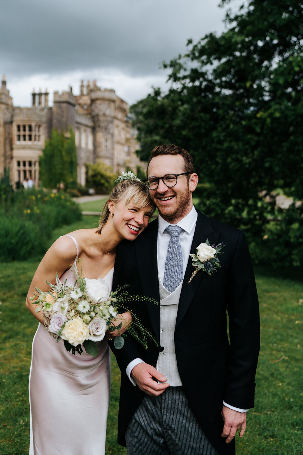  Groom and bride's siter smile during formal photograph with Hawarden Castle in the background 