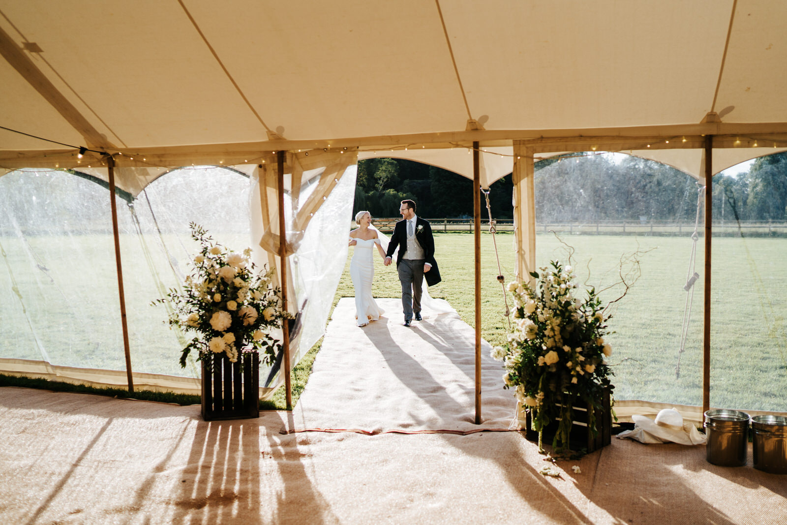 Bride and groom hold hands and look at each other as they are about to enter the wedding marquee