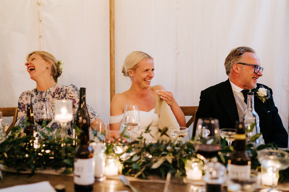  Bride, father of the bride and mother of the bride cannot contain their laughter during the groom's speech 