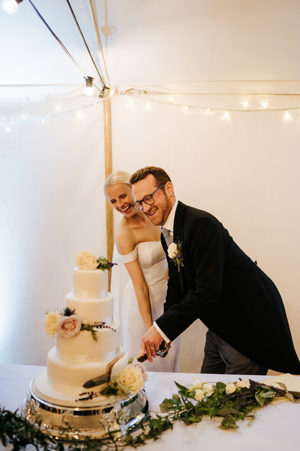  Bride and groom smile as they cut the wedding cake with a sword 