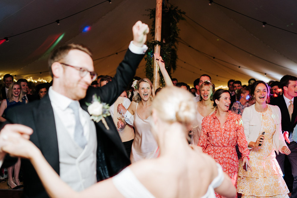  Bride and groom, out of focus in front, finish their first dance and invite guests onto the dancefloor 