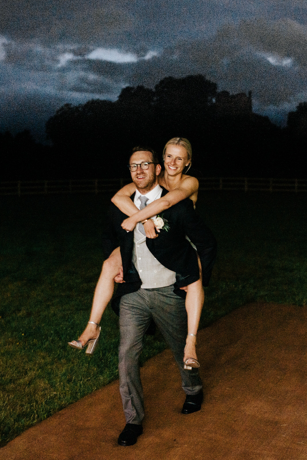 Bride rides "piggyback" style on groom as she re-enters marquee after wardrobe change