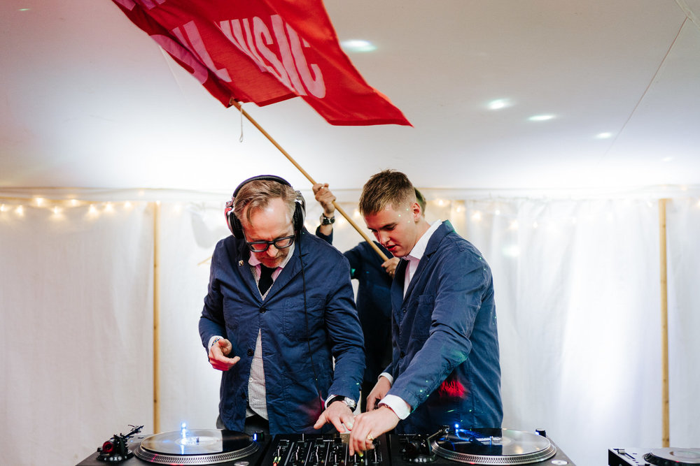  Father of the bride and brothers of the bride DJing behind the decks and waving a big red fan 