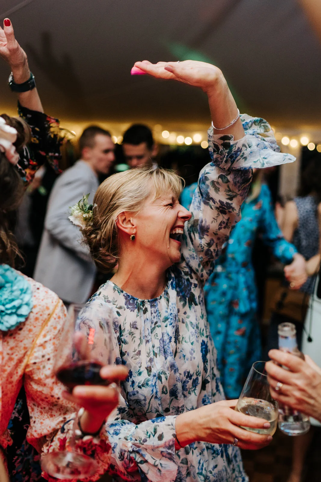Mother of the bride having the time of her life on the dancefloor smiling and throwing her hand in the air