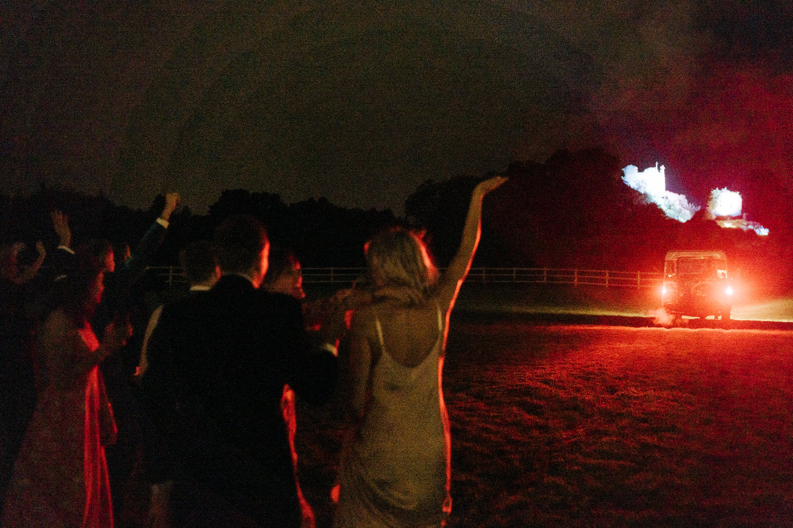 Guests wave off the bride and groom as they drive off in their Range Rover