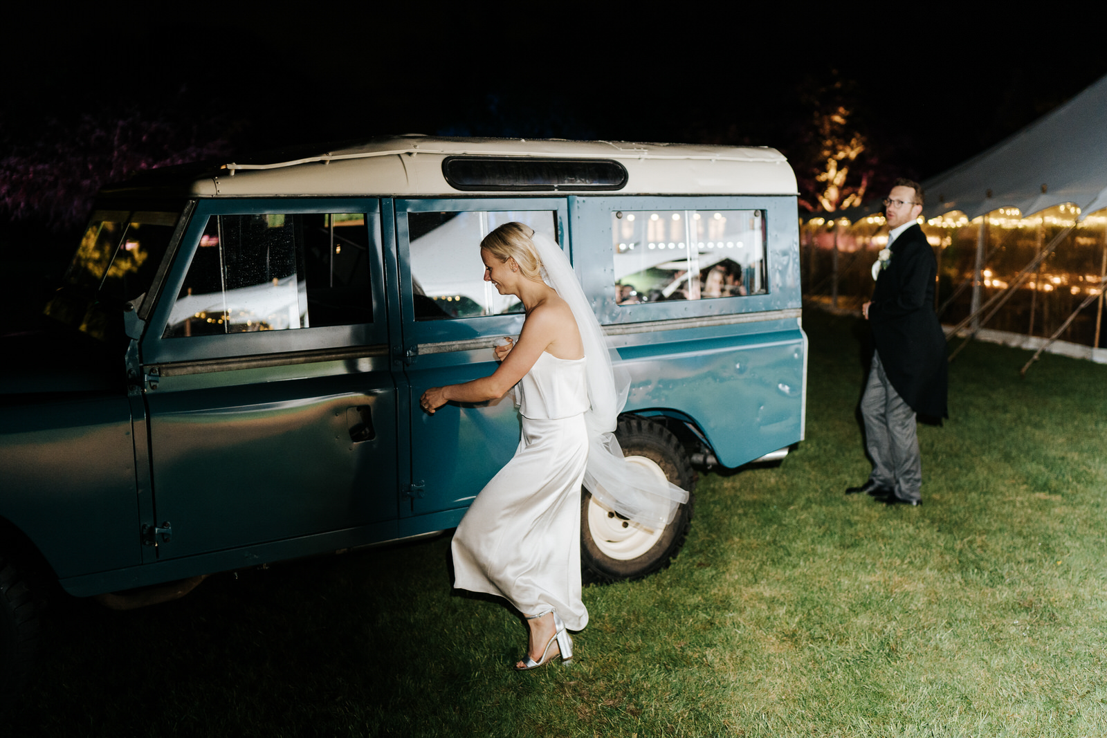 Bride and groom exit marquee and run towards Land Rover to make their wedding exit