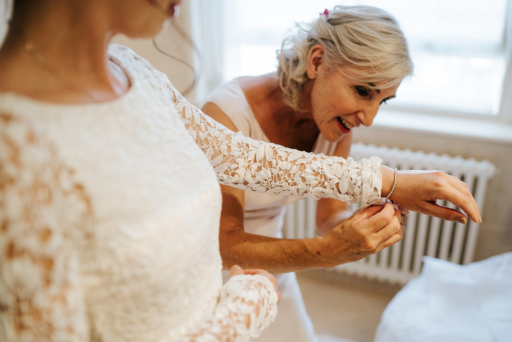  Mother of the bride helps bride put on a bracelet as she finishes getting in her dress 