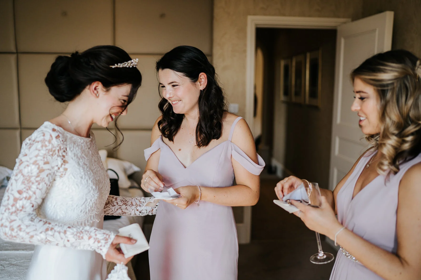 Bridesmaids smile and react to receiving a gift from the bride