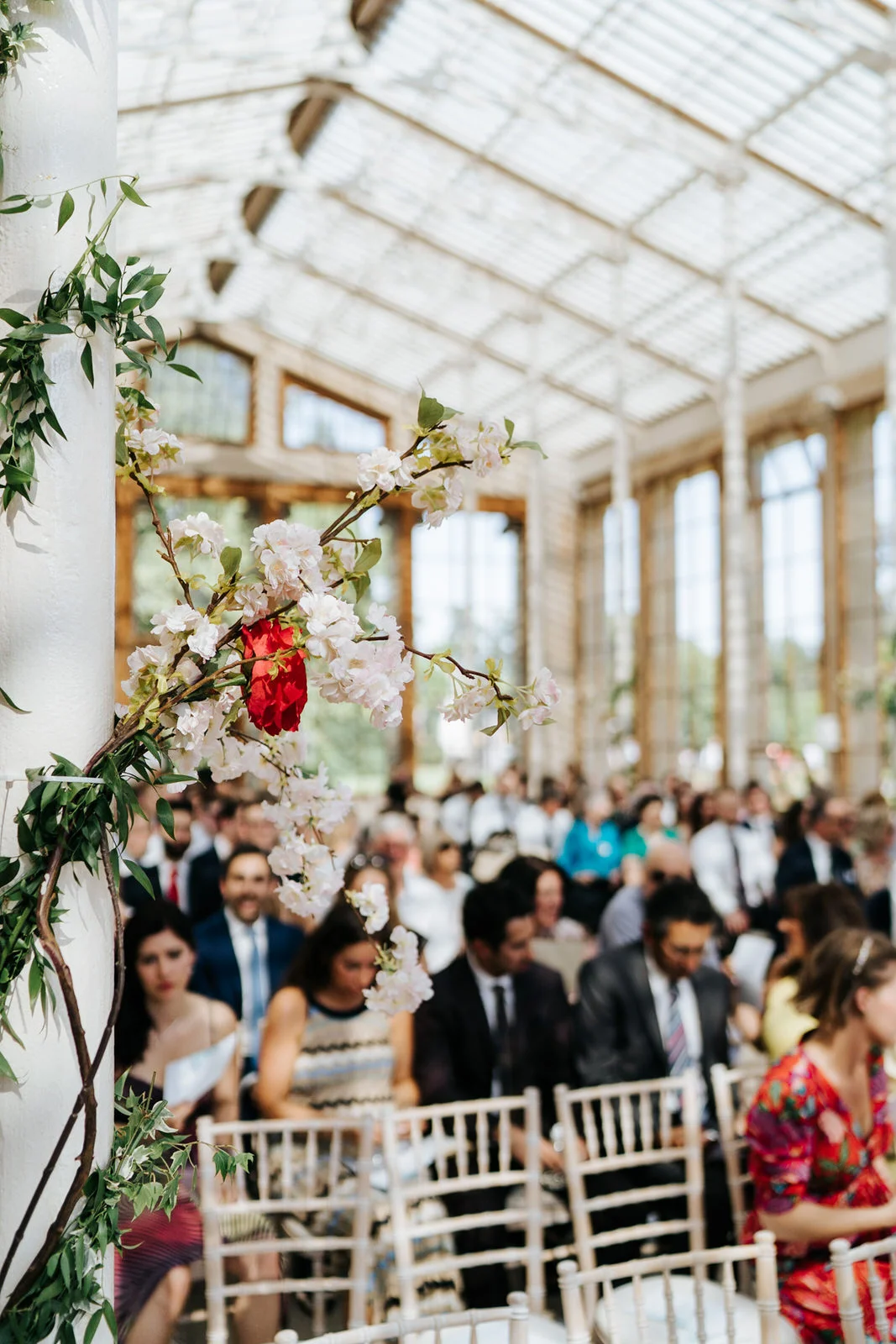 Detail photograph of flowers set up in the Nash Conservatory in Kew Gardens as guests sit in the background, out of focus