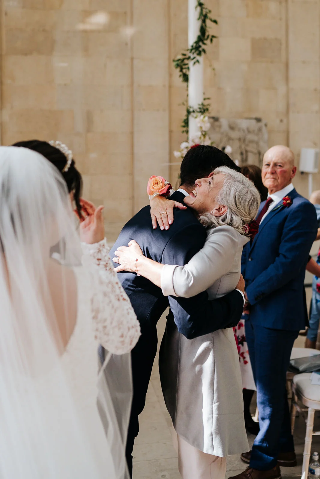 Mother of the bride embraces the groom at the front of the aisle