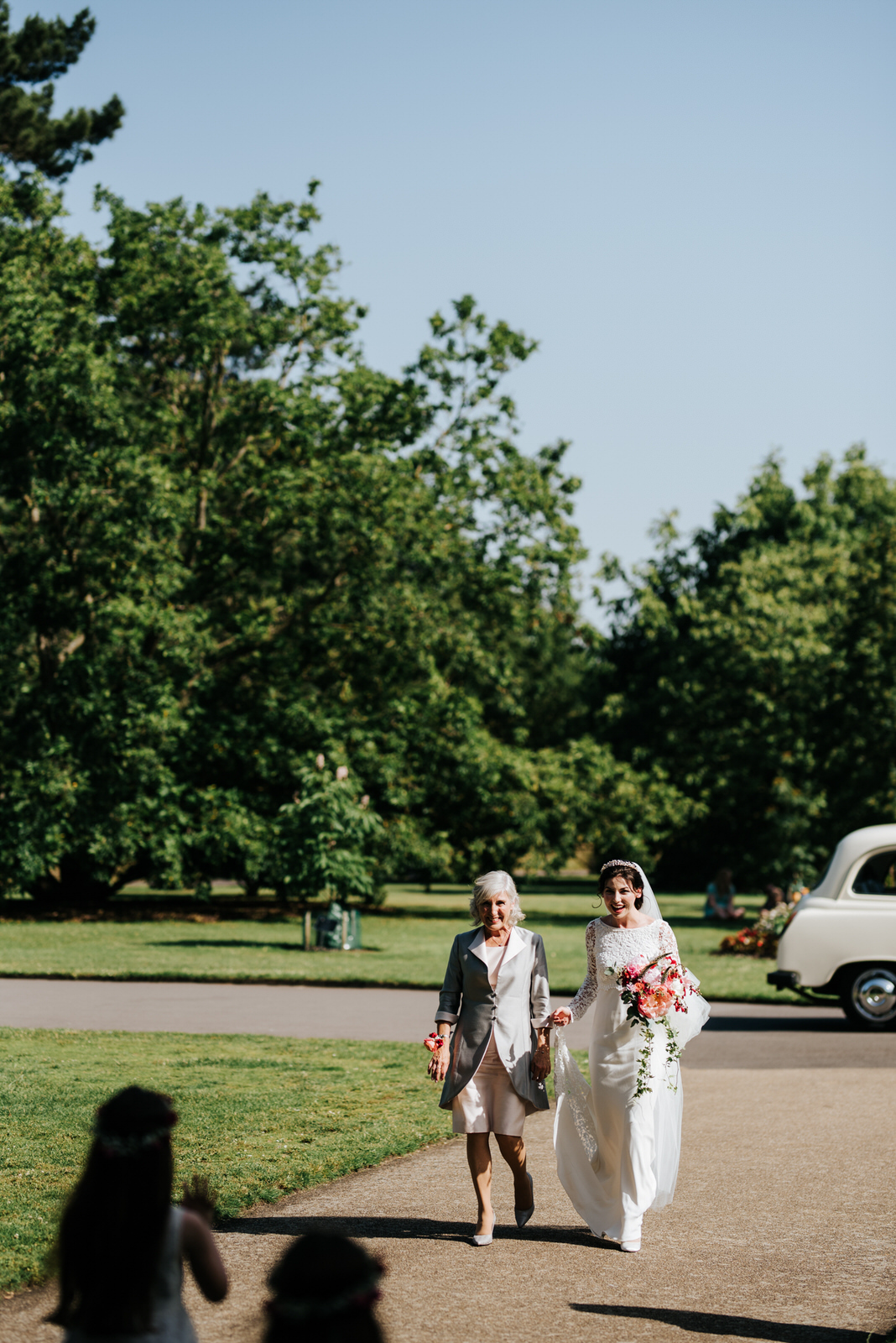  Bride walks towards her bridesmaids and flower girls waiting outside of the Nash Conservatory 