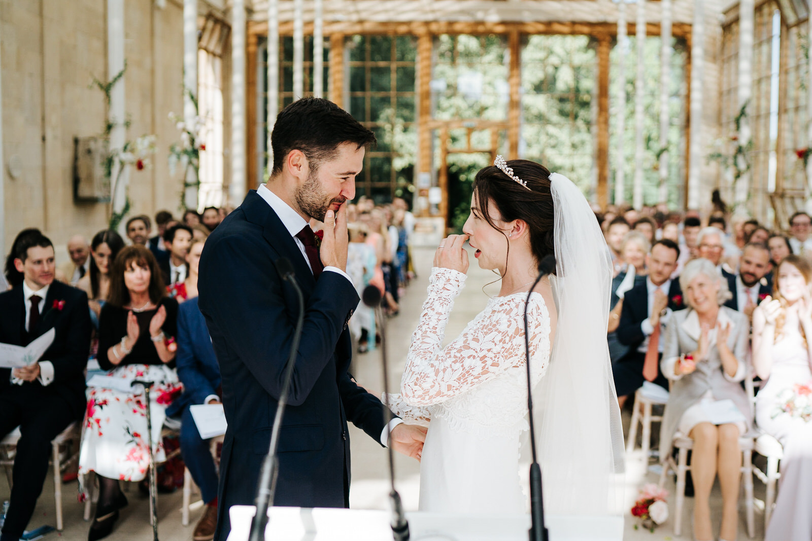  Bride and groom smile at each other and touch their lips seconds after the first kiss 