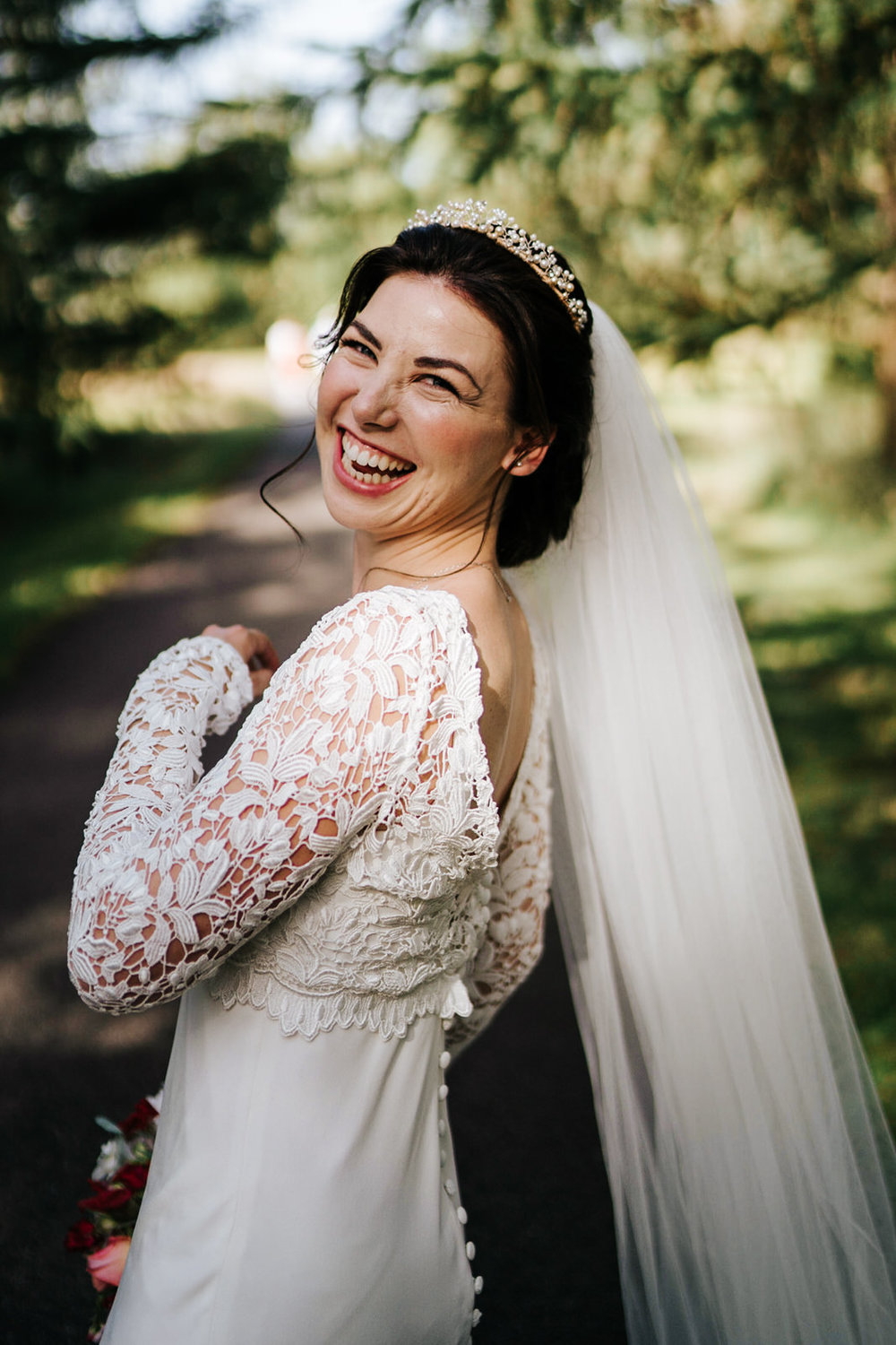  Bride looks at camera over her shoulder and cannot contain her smile and excitement 