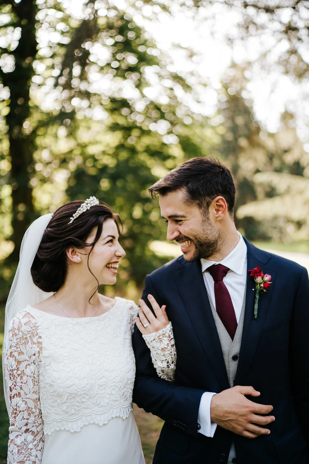 Bride and groom stand in beautiful light in Woodlands area in Kew Gardens and pose for a photograph as bride's veil takes up bottom half of the image