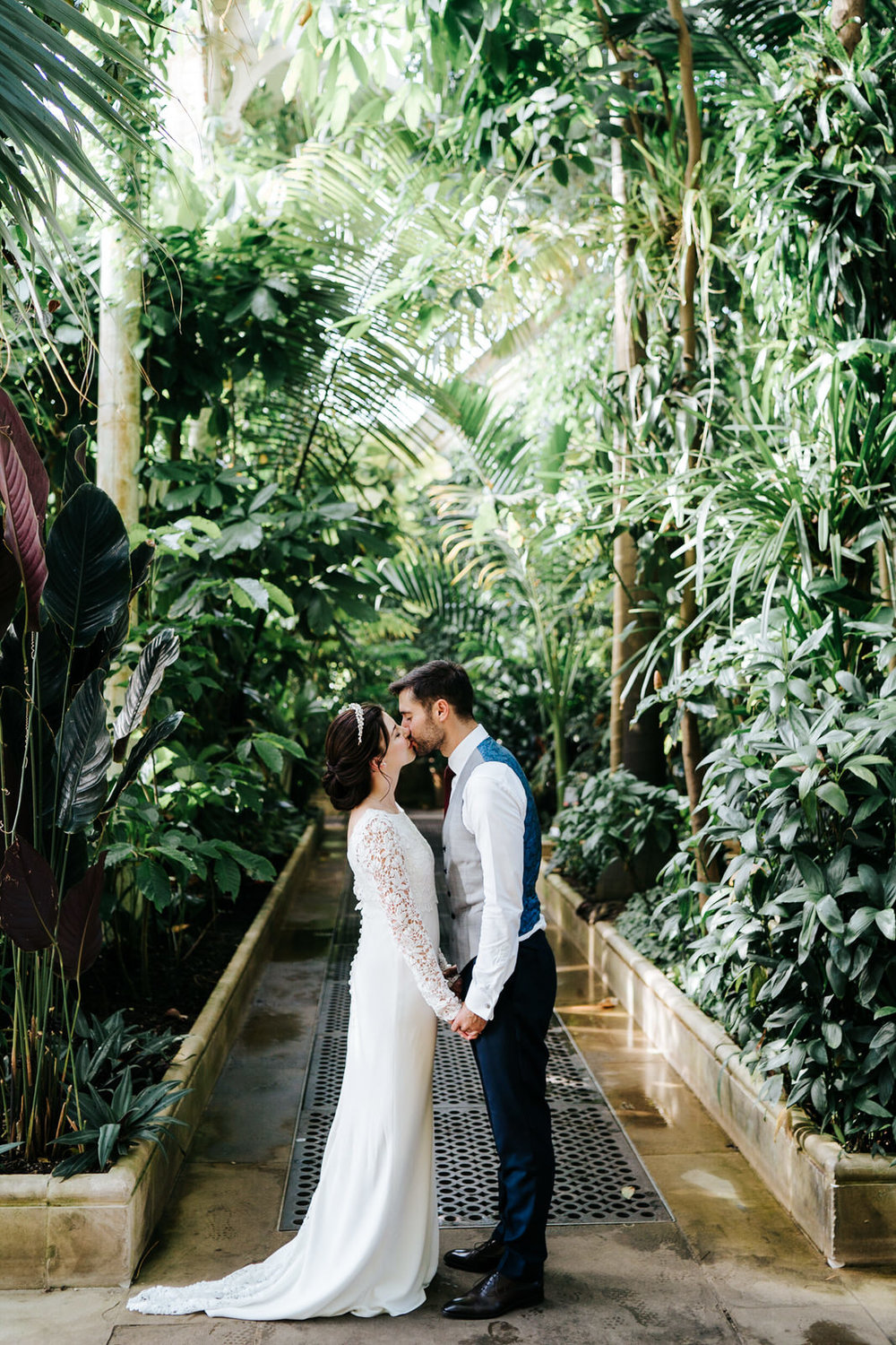  bride and groom kiss and hold hands for a posed photograph inside the Palm House at Kew Gardens 