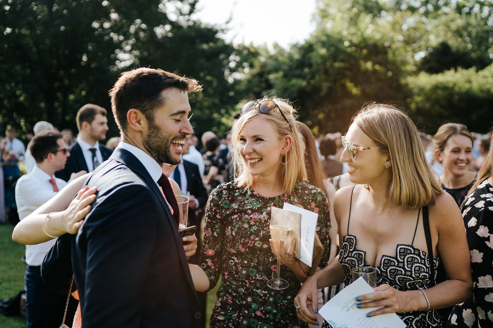 Groom talks to and smiles with a few guests during the wedding drinks reception at Kew Gardens