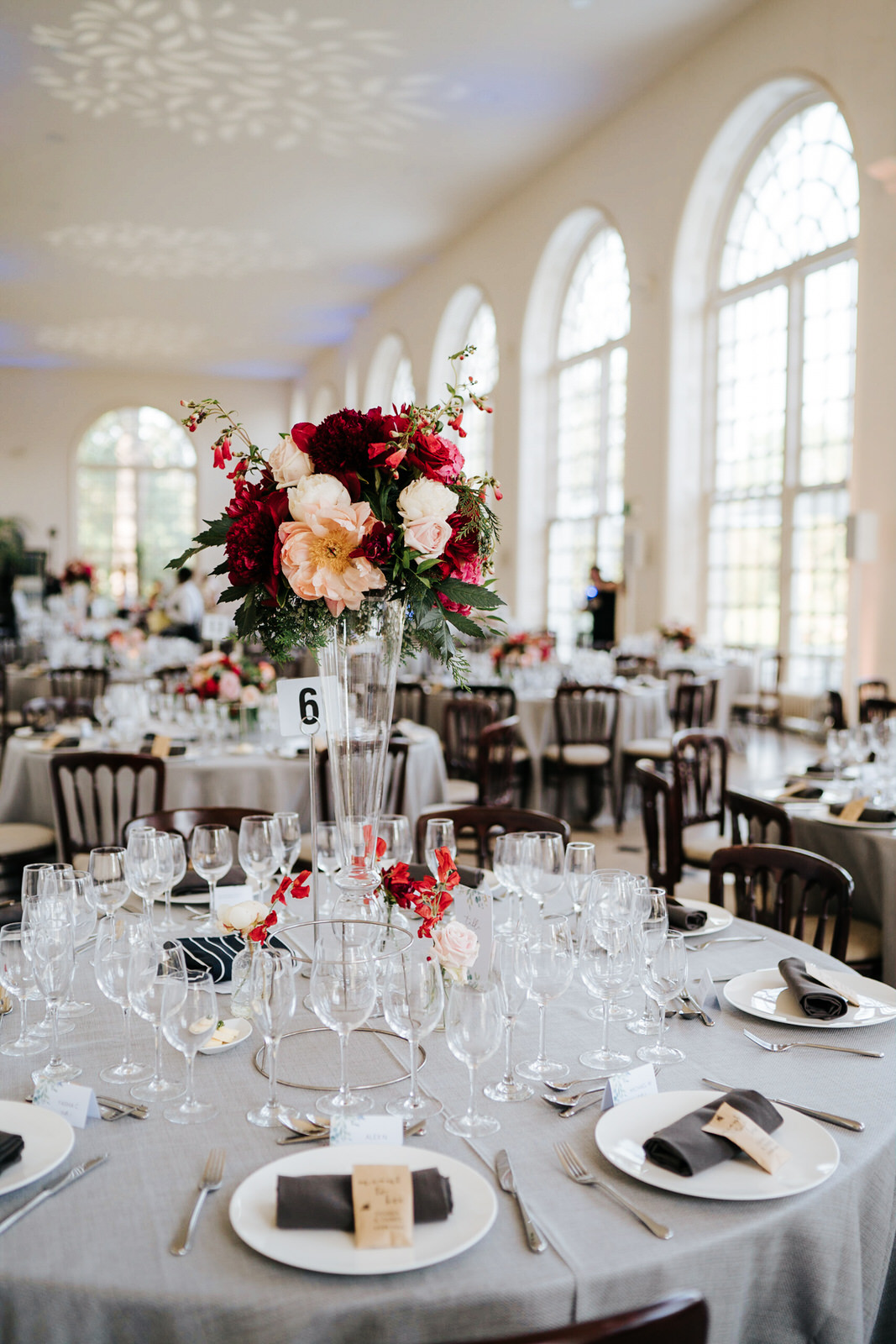  Wide shot of table setup for wedding breakfast at the orangery in kew gardens focusing on beautiful red and white flower centrepieces 