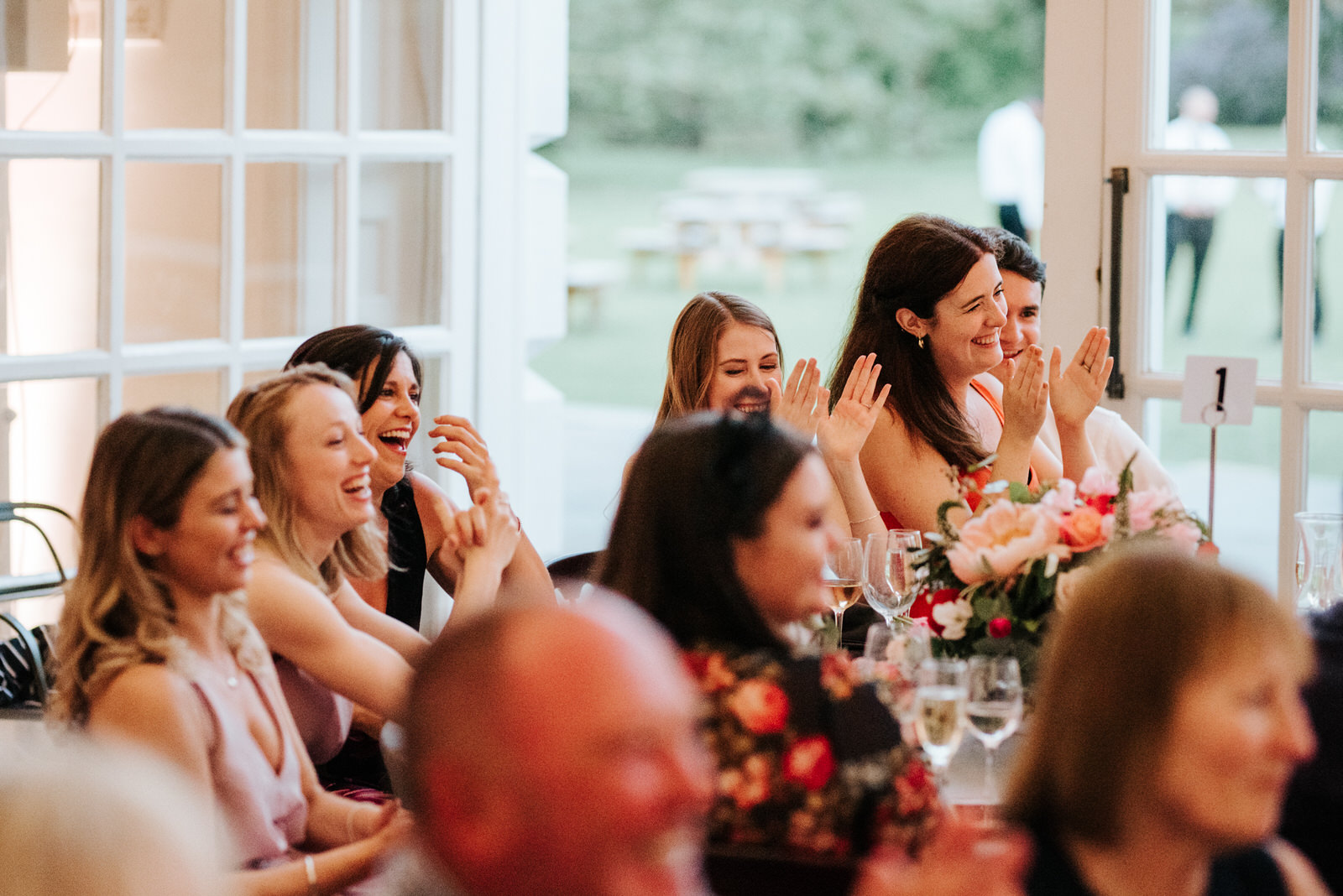  Guests and bridesmaids clap and smile as they react to mother of the bride speech 