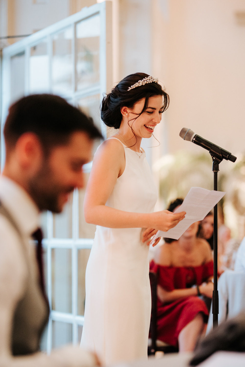  Bride stands and smiles as she delivers her wedding speech 