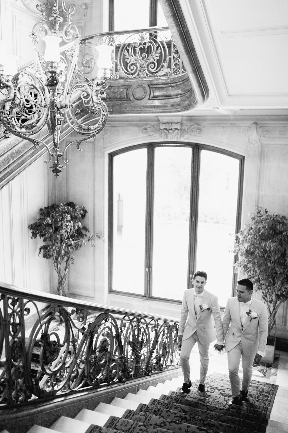  Both grooms walk up stairs in Paris courthouse towards their ceremony room 