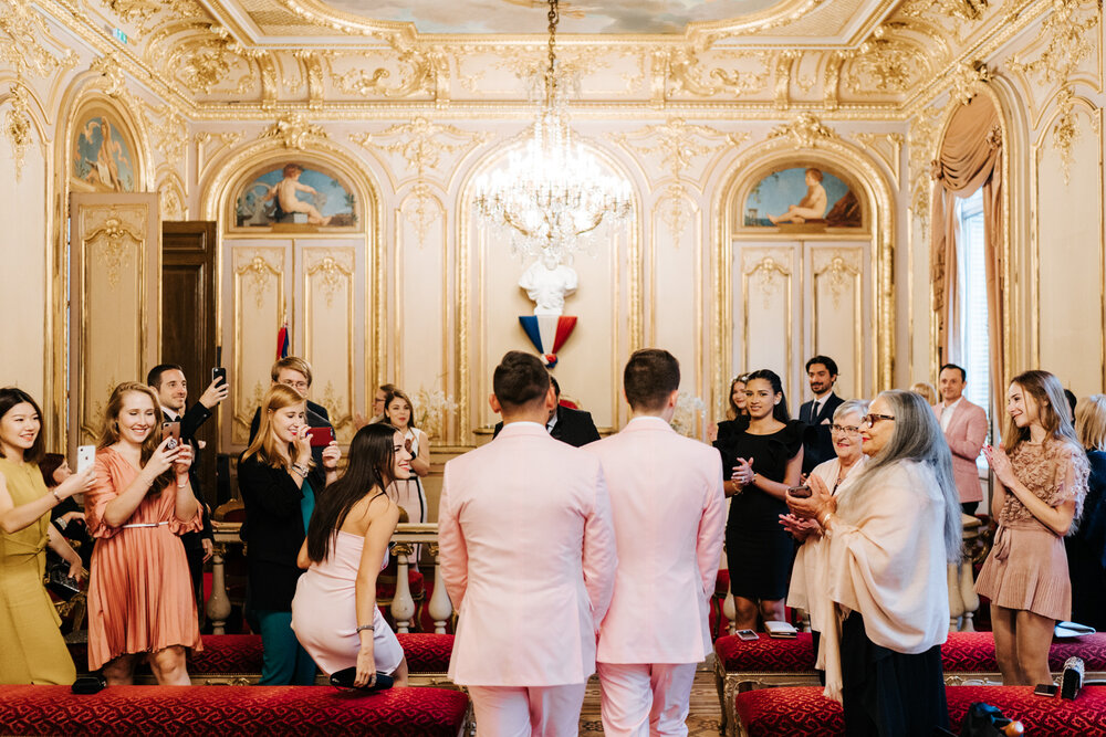  Grooms walk down the aisle, hand in hand, in beautiful ornate ceremony room in Paris 
