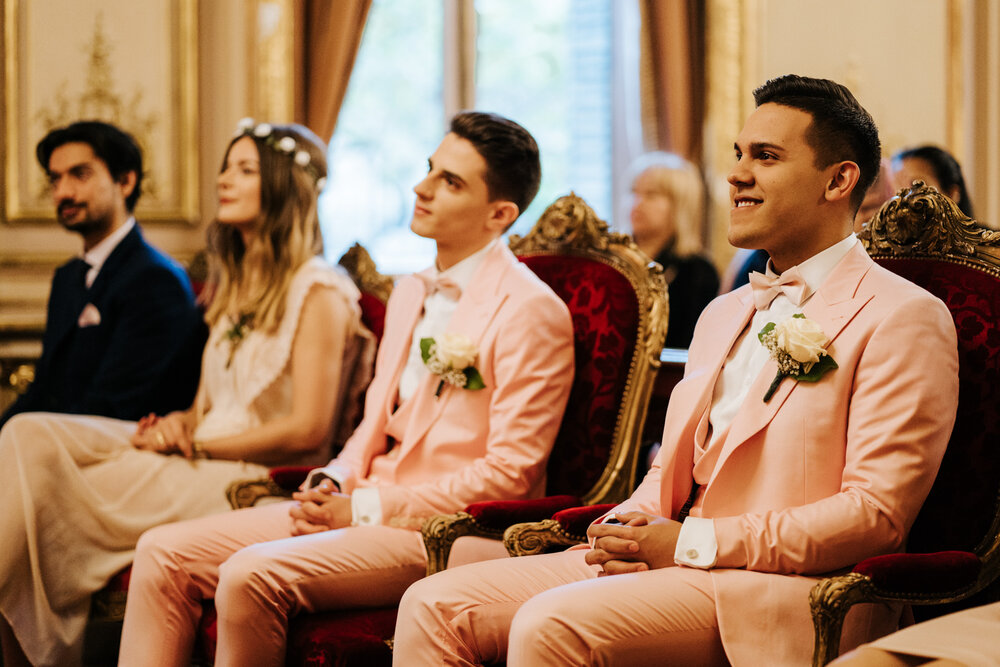  Both grooms pay attention to officiant as wedding ceremony comes to an end 
