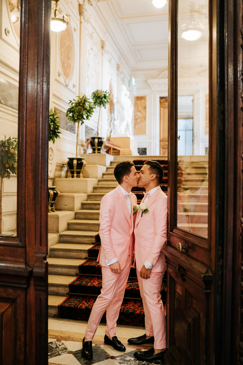  Both grooms kiss inside doorway at Paris courthouse 