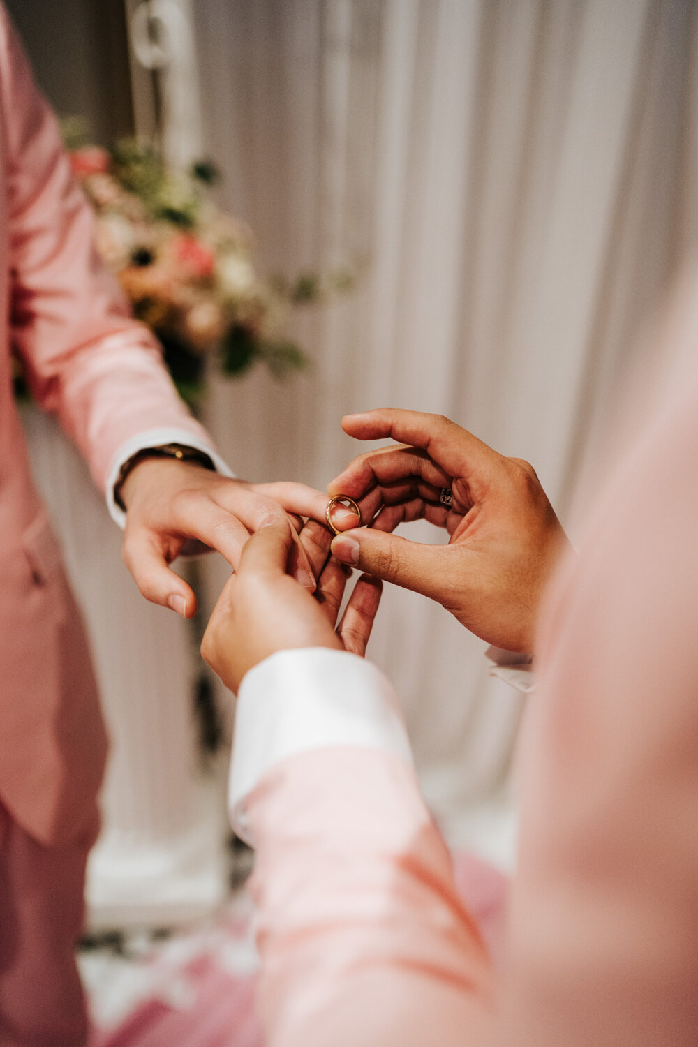  One of the grooms placing the wedding band on the other groom's finger 