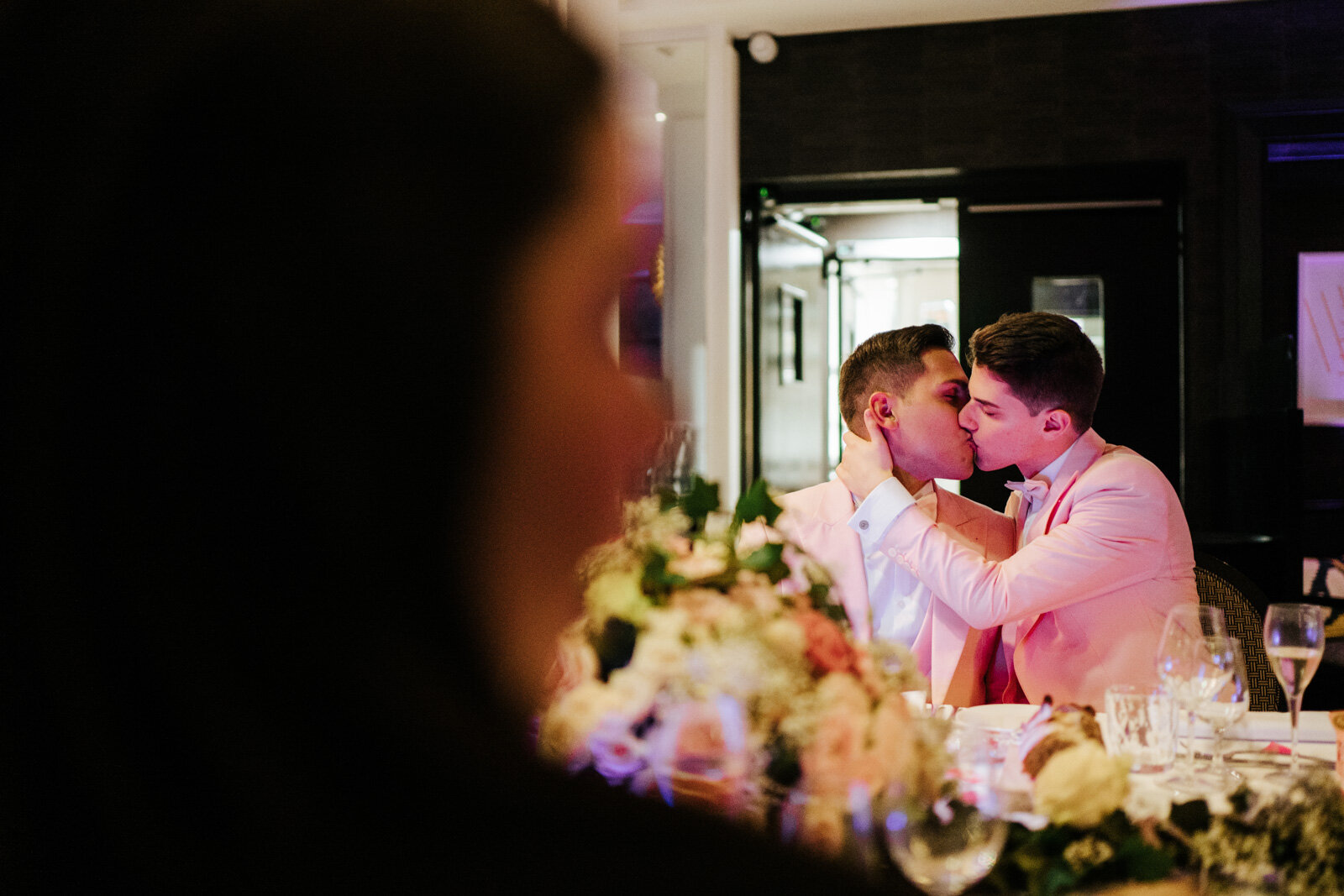  Both grooms kissing at dinner table 