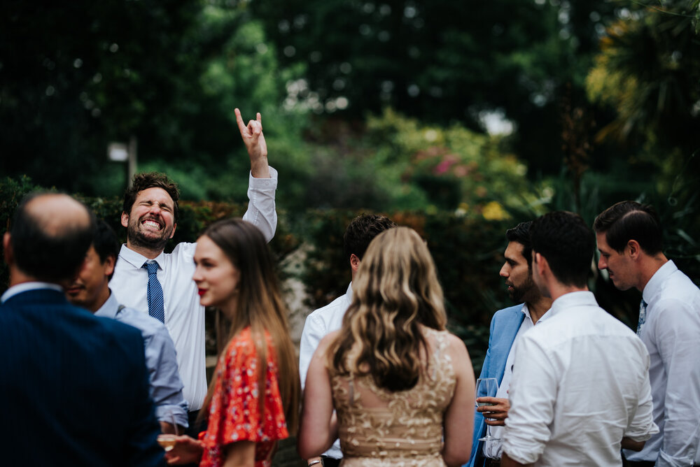 Guest throws his hands into the air with rocker gesture during wedding reception