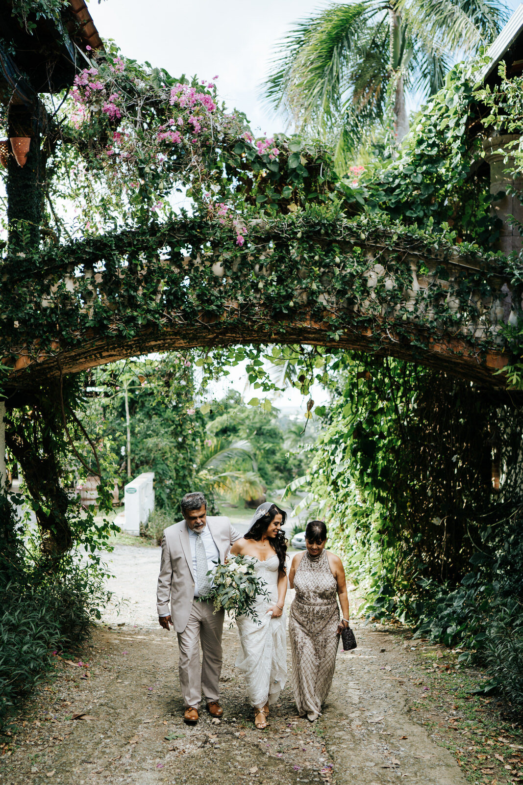 Bride walks to wedding ceremony with her dad and mom at beautiful, lush Puerto Rican wedding venue