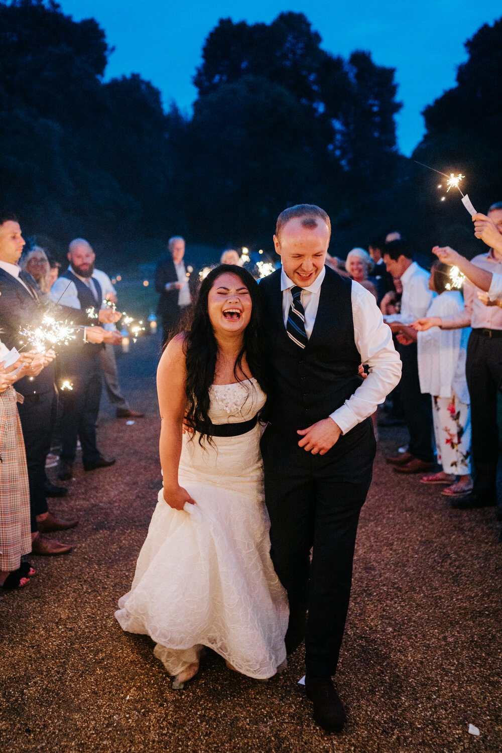 Bride and groom smile as they walk through tunnel of sparklers in Syon Park House London 