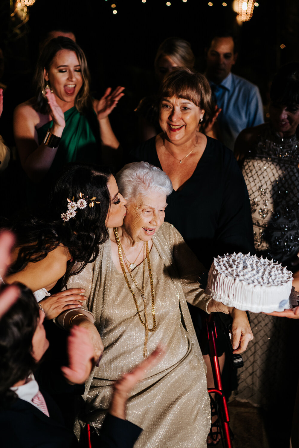 Bride kisses her grandma on the cheek as family celebrates her birthday at wedding
