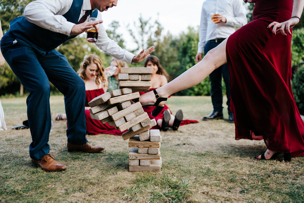Guests play Jenga as one of the guests kicks the tower of blocks