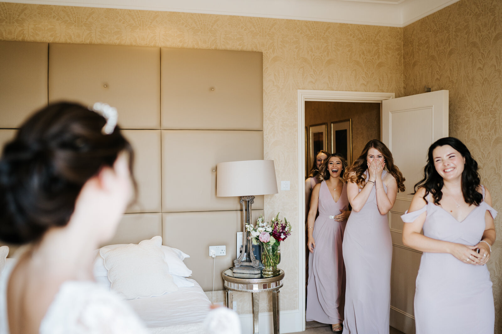 Bridesmaids see bride in her dress for the first time and are incredibly excited 