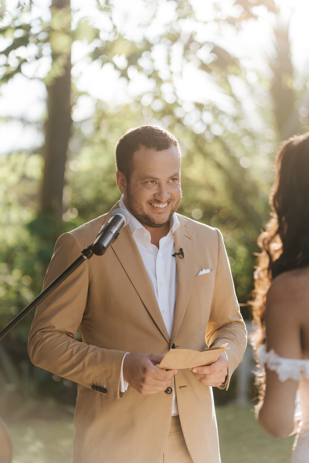 Grooms is very excited in sunlit photograph as he is about to start reading vows during outdoor Puerto Rican ceremony