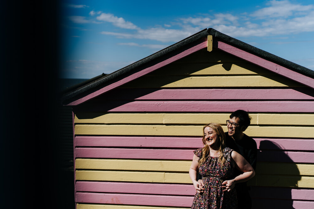 Couple embraces each other in front of colorful house at English seaside town