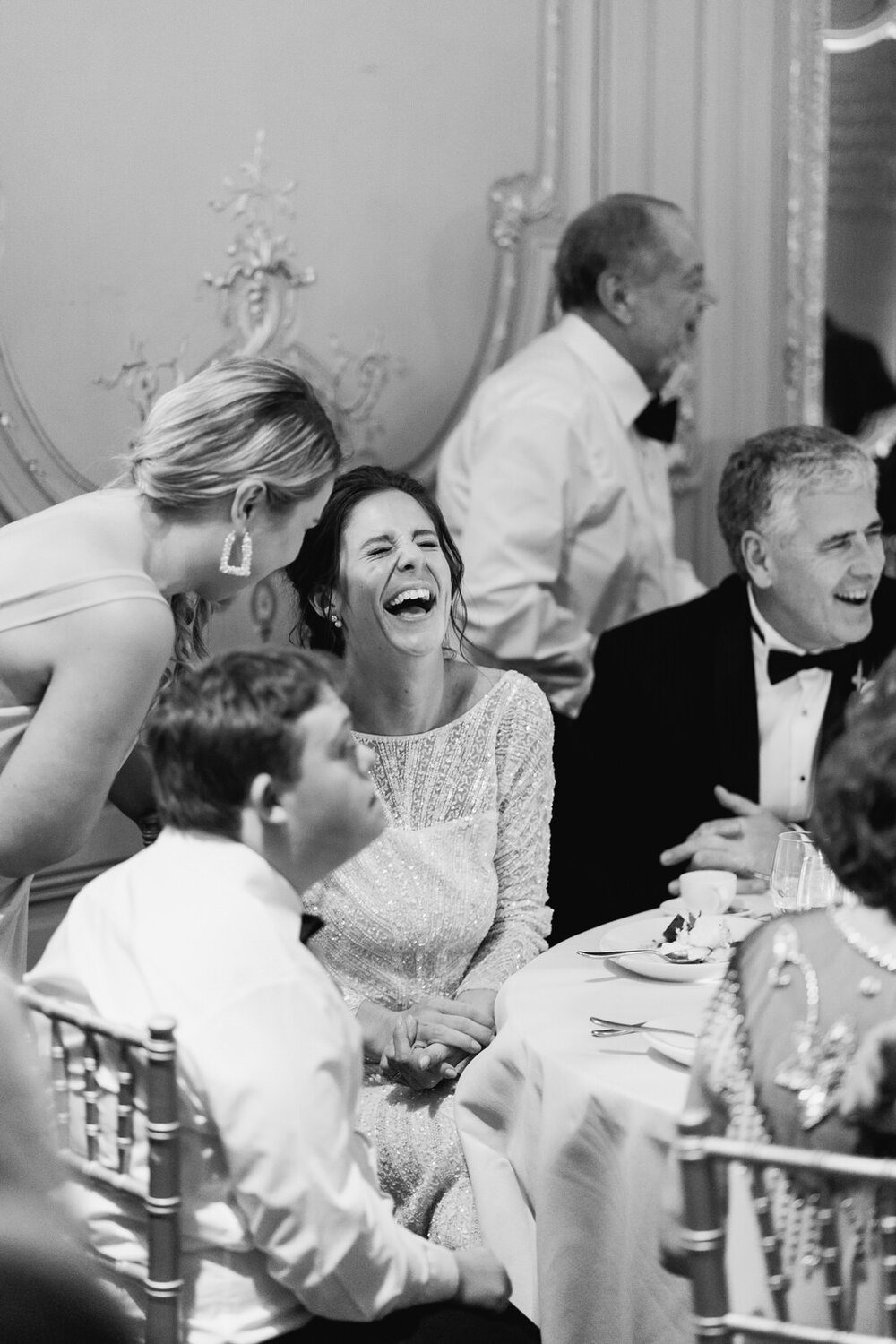 Bride, brother and friends sit at table and talk and laugh with each other after meal 