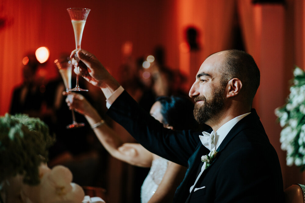 Groom toasts in dramatic light during the speeches