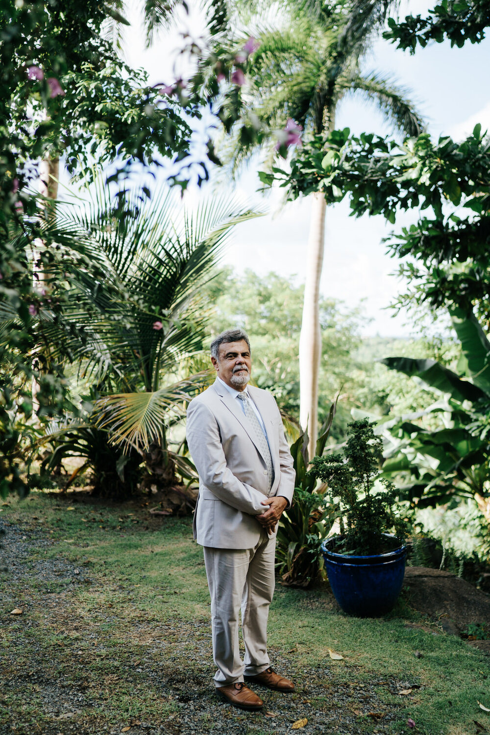 Father of the bride stands outside, surrounded by lush foliage,  (Copy)