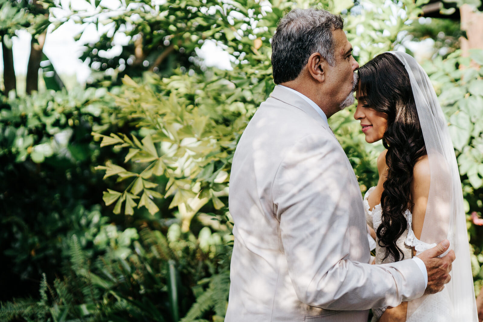 Father of the bride holds her by the arms and kisses her forehea (Copy)