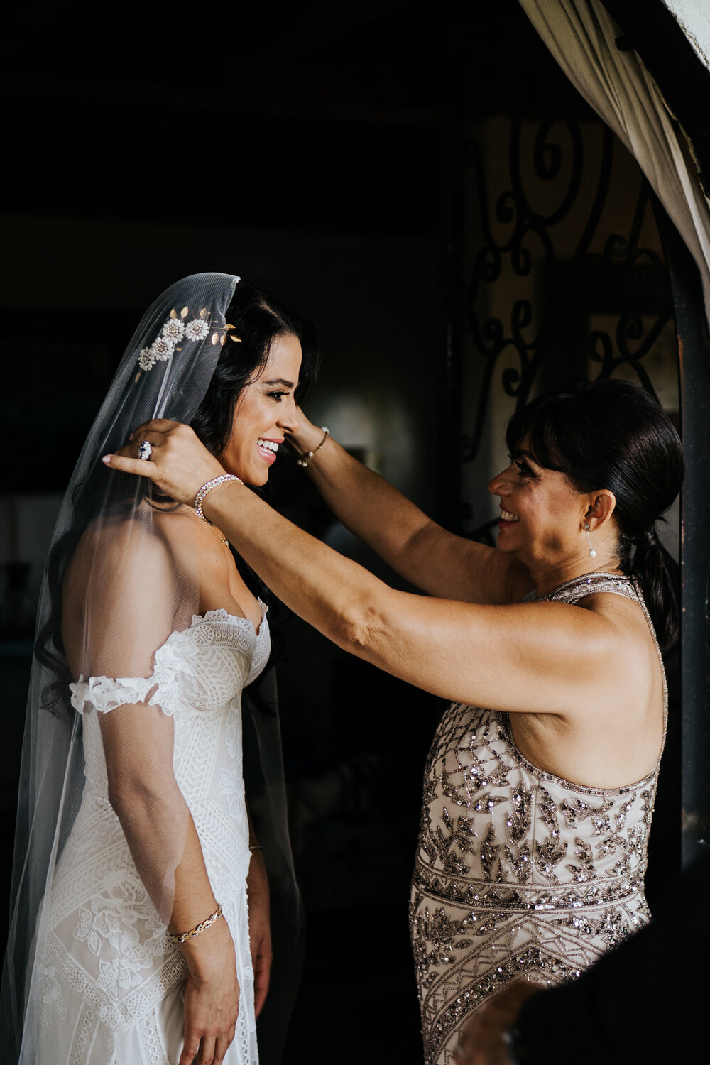 Mother of the bride positions the bride's veil as they both smil (Copy)