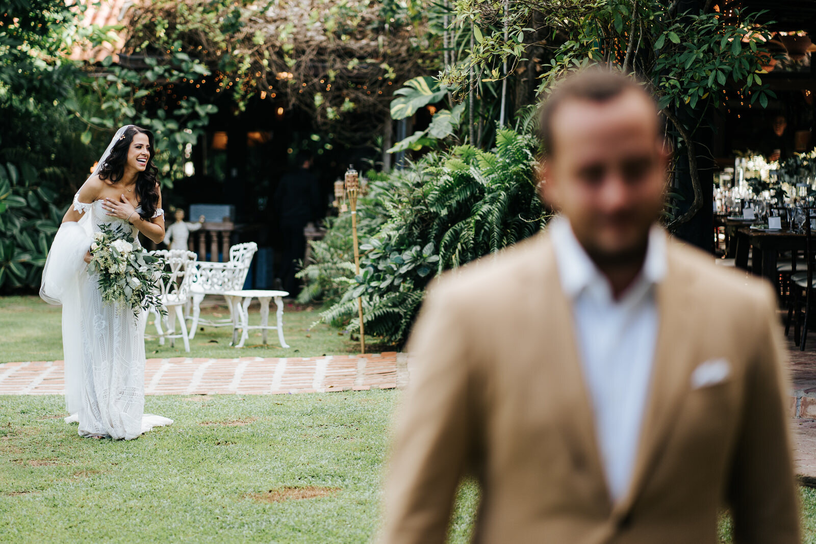 Bride stands behind groom, who is out of focus, as she smiles an (Copy)