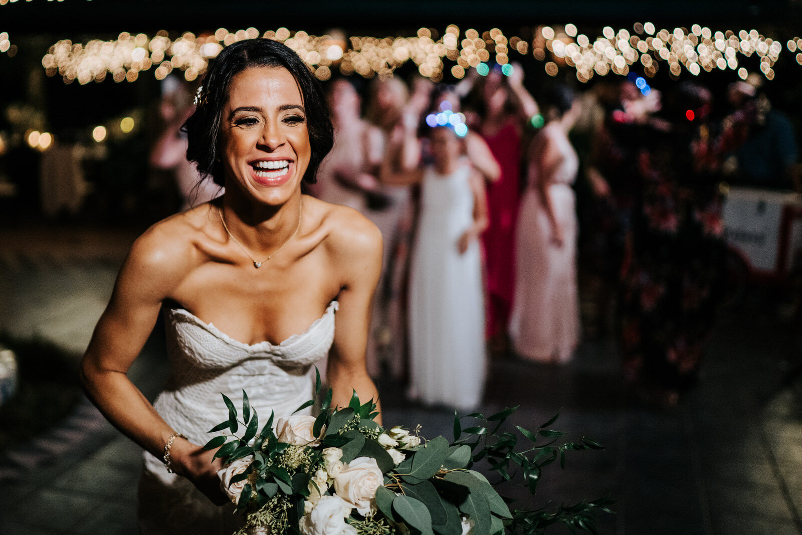 Bride smiles and holds bouquet as she gets ready to throw it to  (Copy)