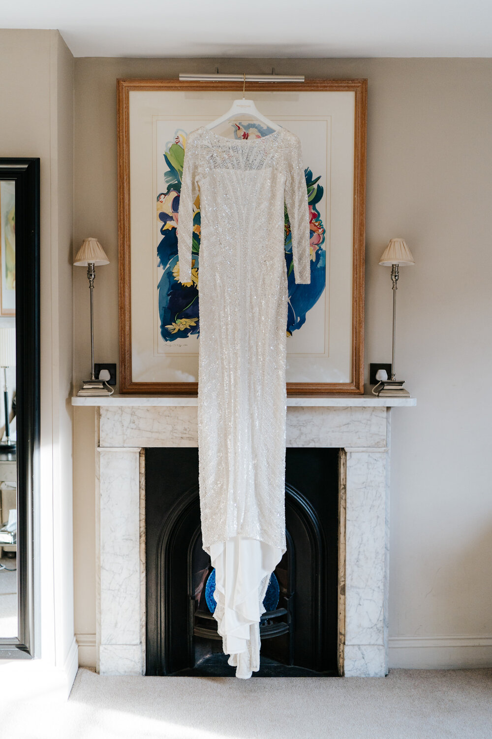Bride's elegant dress hangs in room at Savile Club London during preparations