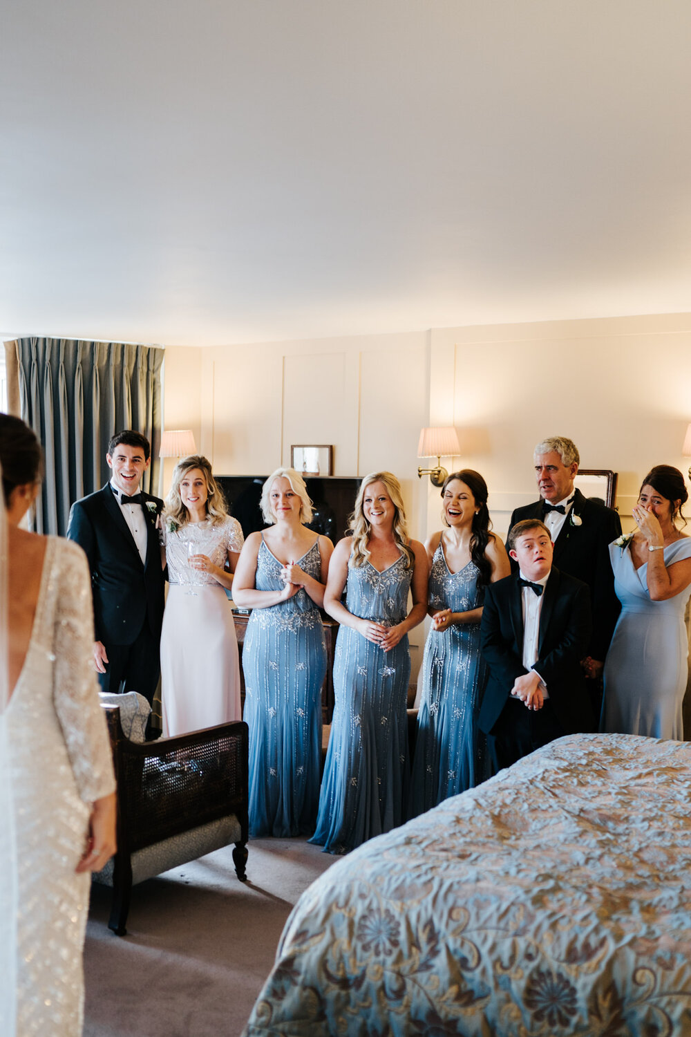 Bridesmaids and parents of the bride react joyfully to seeing bride in her dress